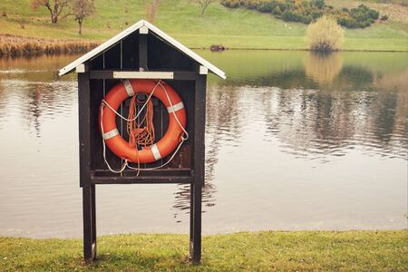 Lifebelt with rope next to a lake. Copy space