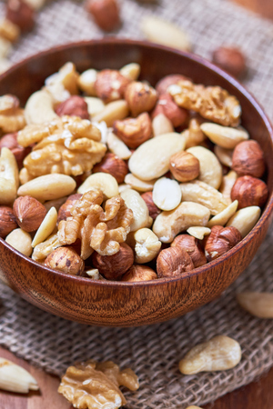 Mixed nuts including hazelnuts, walnuts, blanched almonds and cashews in wooden bowlの写真素材