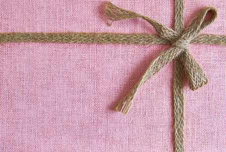 Pink background with burlap ribbon and bow. Top view with copy spaceの写真素材