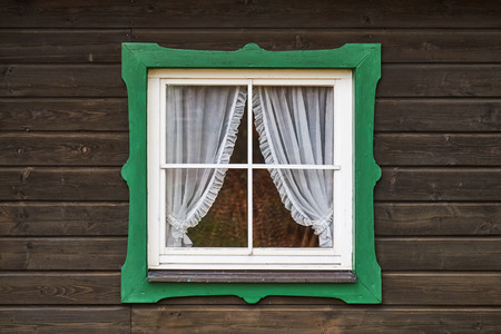 Aged wooden window with green frame on old german wooden hutの写真素材