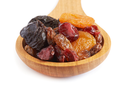 Mix of dried fruits (prunes, raisins, apricots and cranberries) in wooden spoon isolated on white backgroundの写真素材