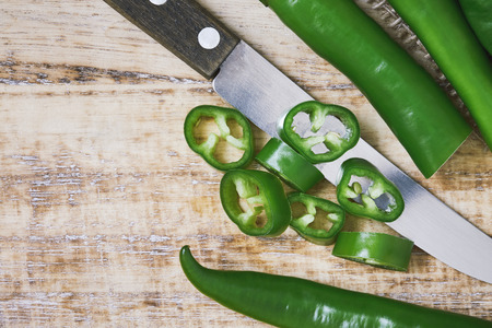 Fresh raw sliced green chili pepper on cutting board. Top view with copy spaceの写真素材