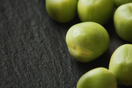 Fresh raw green peas on black rustic background. Copy spaceの写真素材