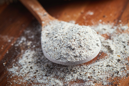 Organic buckwheat flour in wooden spoon on tableの写真素材