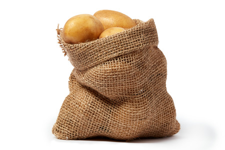 Burlap sack of fresh raw potatoes isolated on white backgroundの写真素材