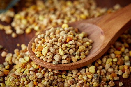 Close up of bee pollen grains in wooden spoon