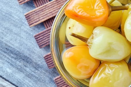Pickled preserved bell peppers in glass bowl on wooden backgroundの写真素材