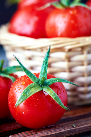 Fresh ripe organic tomatoes with water drops on wooden backgroundの写真素材