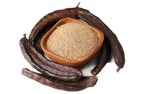 Ground carob (Ceratonia siliqua) powder with carob bean pods isolated on white backgroundの写真素材