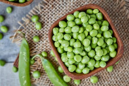 Fresh raw organic green peas (Pisum sativum) in wooden bowl. Top viewの写真素材