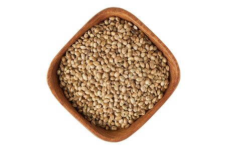 Organic whole hemp seeds in wooden bowl isolated on white backgroundの写真素材