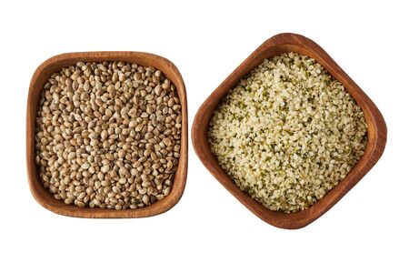 Organic whole and shelled hemp seeds in wooden bowl  isolated on white backgroundの写真素材