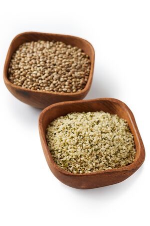Organic whole and shelled hemp seeds in wooden bowl  isolated on white backgroundの写真素材