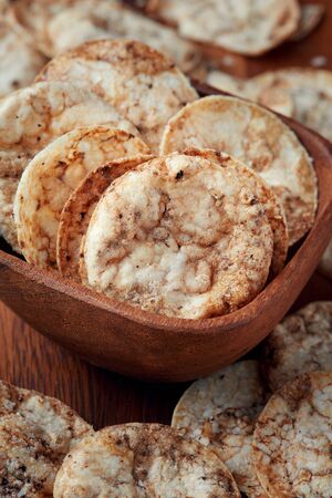 Brown rice chips in wooden bowl. Healthy crispy snackの写真素材