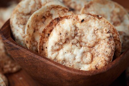 Brown rice chips in wooden bowl. Healthy crispy snackの写真素材