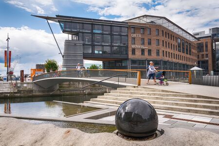Oslo, Norway - July 18, 2016: People enjoying the summer sunshine beside the al fresco restaurants and modern apartment buildings of Aker Brygge, the popular leisure district on the Oslo waterfront overlooking the marinas of Oslofjrden, Norway.のeditorial素材