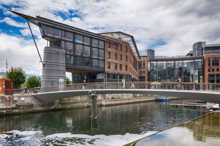 Oslo, Norway - July 18, 2016: People enjoying the summer sunshine beside the al fresco restaurants and modern apartment buildings of Aker Brygge, the popular leisure district on the Oslo waterfront overlooking the marinas of Oslofjrden, Norway.のeditorial素材