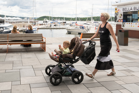Oslo, Norway - July 18, 2016: People enjoying the summer sunshine beside the al fresco restaurants and modern apartment buildings of Aker Brygge, the popular leisure district on the Oslo waterfront overlooking the marinas of Oslofjrden, Norway.のeditorial素材