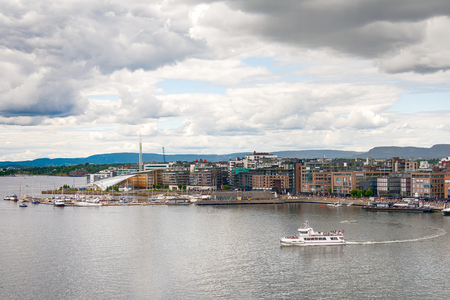 Oslo, Norway - July 18, 2016: People enjoying the summer sunshine beside the al fresco restaurants and modern apartment buildings of Aker Brygge, the popular leisure district on the Oslo waterfront overlooking the marinas of Oslofjrden, Norway.のeditorial素材