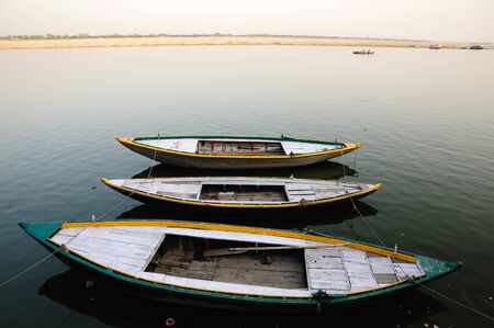 Wooden country boats tied in a row on the bank of river ganga. These boats are used by pilgrims and tourists visiting Varanasi in India.の写真素材