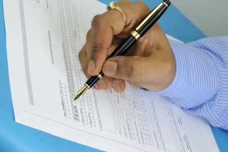 a gentleman filling up an application form for admission with a fountain penの写真素材