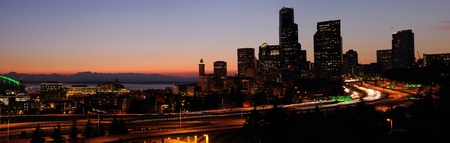 Panoramic image of Seattle downtown buildings and adjoining freeways with sunset glow over the horizonの写真素材