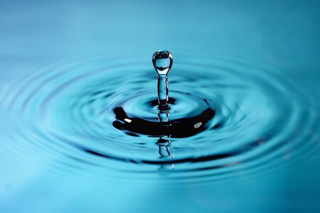 A droplet splashing over calm water macro
