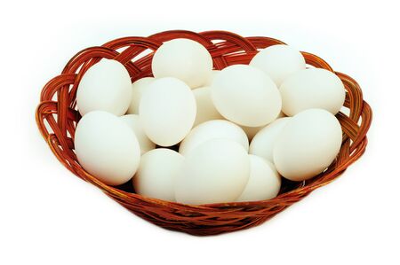 White eggs in a cane basket isolated over white backgroundの写真素材