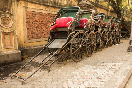 Traditional hand pulled Indian rickshaws parked together in front of a old building in Kolkataの写真素材