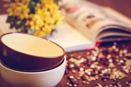 Bowl brown and white, grains, book on a wooden tableの写真素材