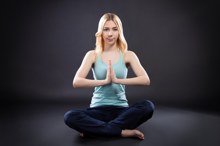 Younger woman makes yoga training in the studio on black backgroundの写真素材