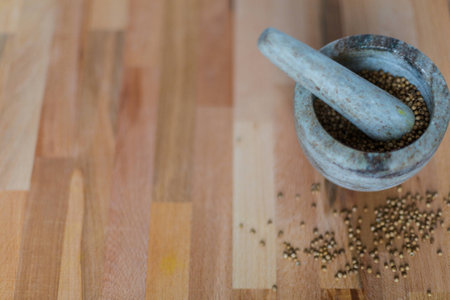 stone mortar with coriander seeds on wooden backgroundの写真素材