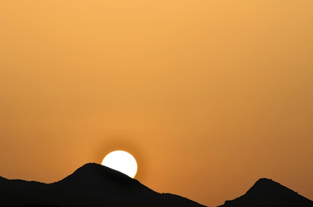 sunset behind the silhouette of the mountainsの写真素材