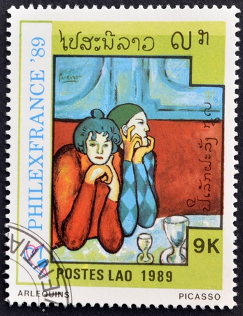 LAOS-CIRCA 1989: A stamp printed in the Laos shows painting "arlequins" by Pablo Picasso, circa 1989 のeditorial素材