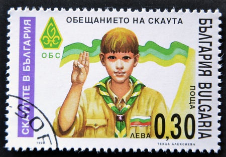BULGARIA - CIRCA 1999: A stamp printed in Bulgaria shows a boy Scout Giving scout sign, circa 1999のeditorial素材
