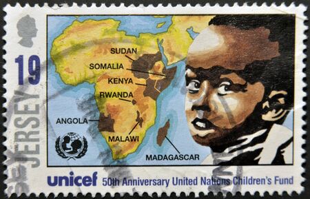 JERSEY - CIRCA 2011: A stamp printed in Jersey dedicated to 50th anniversary united nations childrenÂ´s fund, shows a boy and a map of africa, circa 2011 のeditorial素材