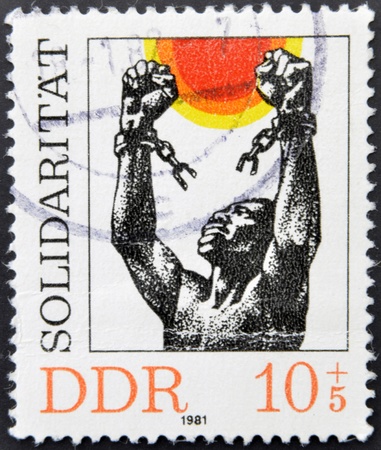 GERMANY (GDR) - CIRCA 1981: A stamp printed in Germany dedicated to international solidarity, shows a black man breaking the chains of slavery, circa 1981の写真素材