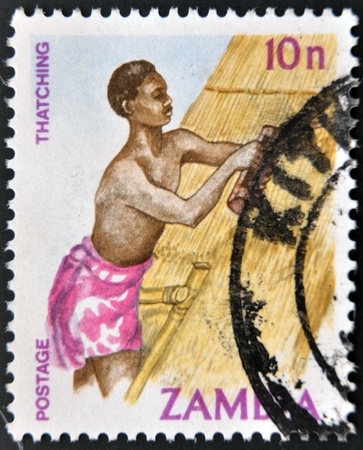 ZAMBIA - CIRCA 1981  A stamp printed in Zambia shows a man thatching home, circa 1981のeditorial素材