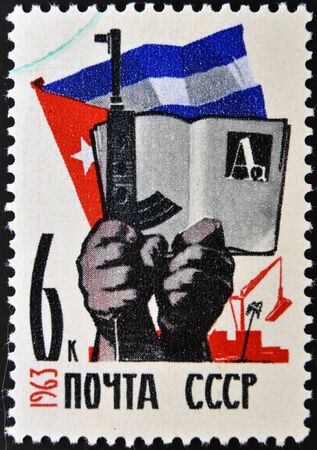 USSR - CIRCA 1963: A stamp printed in Russia shows Cuban flag, hands with gun and book, circa 1963 のeditorial素材
