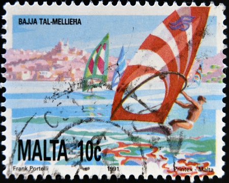 MALTA - CIRCA 1991: A stamp printed in Malta shows windsurfing in Mellieha Bay, circa 1991の写真素材