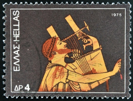 GREECE - CIRCA 1975: A stamp printed in Greece dedicated to the traditional musical instruments shows an ancient guitar player, circa 1975. の写真素材