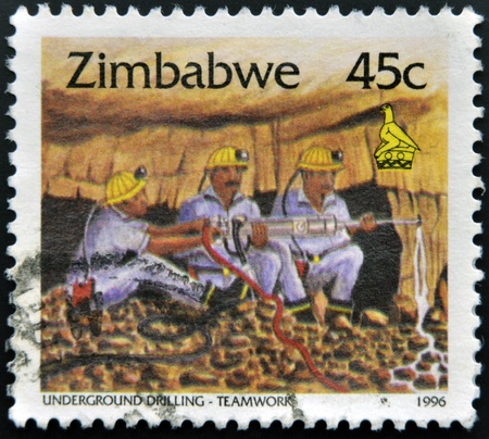 ZIMBABWE - CIRCA 1995: A stamp printed in Zimbabwe shows Underground drilling, teamwork, circa 1995 の写真素材