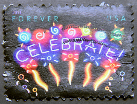 UNITED STATES OF AMERICA - CIRCA 2011: A postage stamp of USA shows neon celebrate! sign with fireworks on black backgroundのeditorial素材