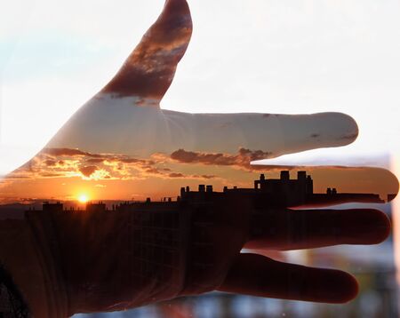 Hand and sunset in the city. Double exposure taken with the cameraの写真素材