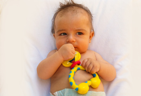 3 months old baby boy playing with teething toyの写真素材