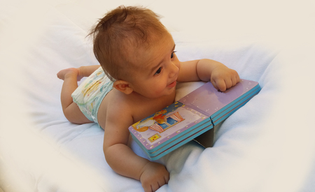 4 monyhs old baby playing with bookの写真素材
