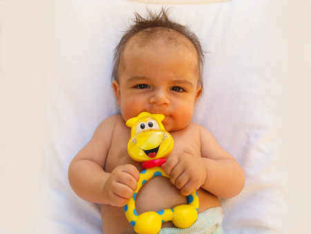 3 months old baby boy playing with teething toyの写真素材