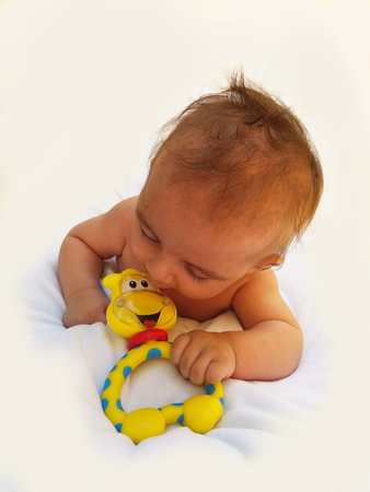 3 months old baby boy playing with teething toyの写真素材