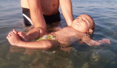 four month old baby boy first time swimming in the sea