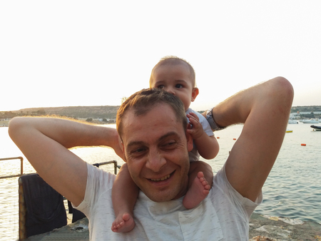 four month old baby boy sitting on daddy s neckの写真素材